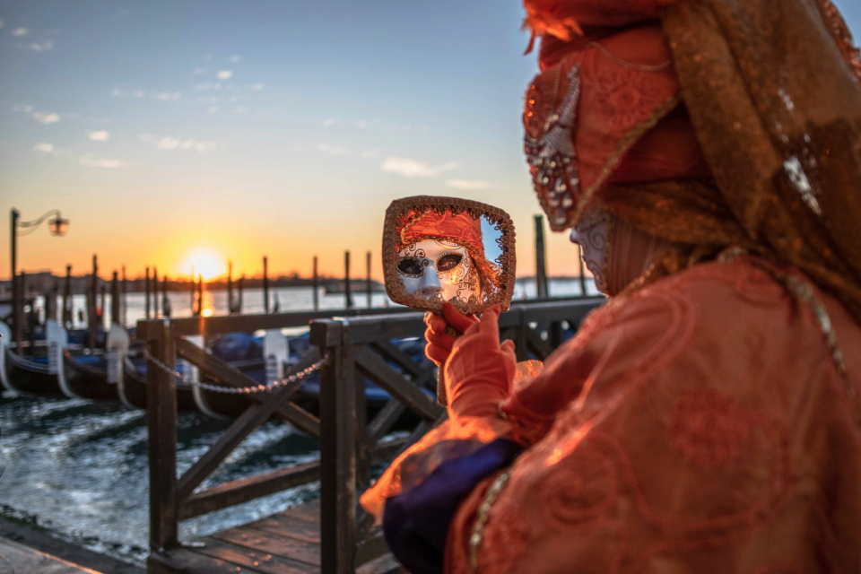 People category A woman in traditional celebration festival attire admires her reflection in a mirror as the sun sets in Venice, by Mia Feres